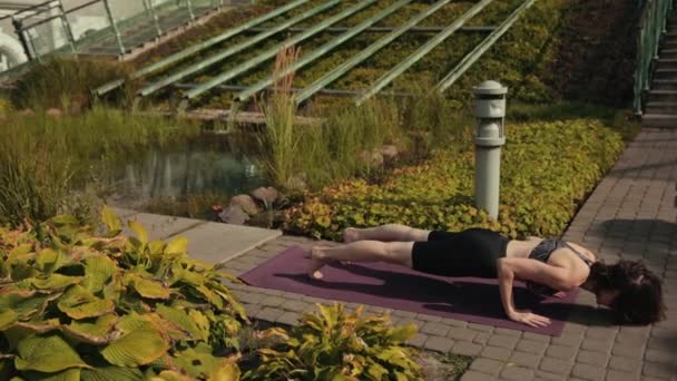 Chica joven en ropa deportiva negro haciendo yoga al aire libre, realiza varios ejercicios — Vídeos de Stock