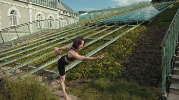 Chica joven en ropa deportiva negro haciendo yoga al aire libre, realiza varios ejercicios — Vídeo de stock