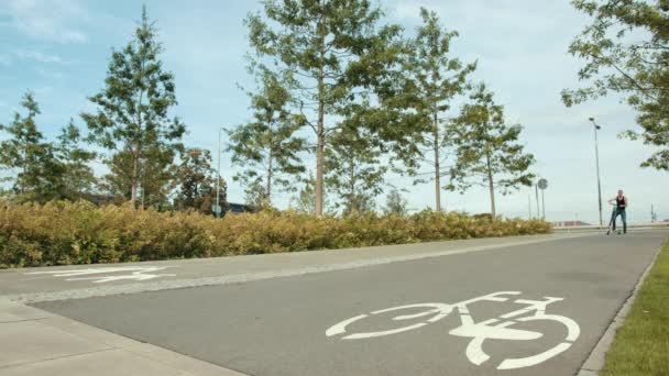 Man in zwarte kleren en jeans, rijden rond de stad op een elektrische scooter — Stockvideo