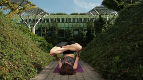 Jovem no sportswear preto fazendo ioga ao ar livre, executa vários exercícios — Vídeo de Stock