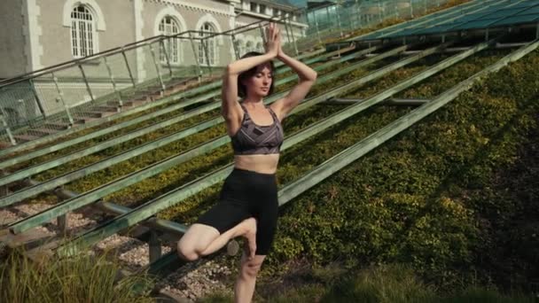 Chica joven en ropa deportiva negro haciendo yoga al aire libre, realiza varios ejercicios — Vídeos de Stock