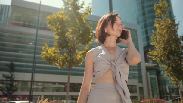 Företag, ung kvinna, brunett, hålla en smartphone prata, positiv attityd — Stockvideo
