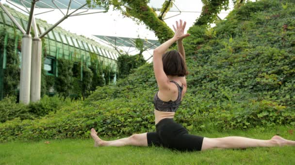 Chica joven en ropa deportiva negro haciendo yoga al aire libre, realiza varios ejercicios — Vídeos de Stock