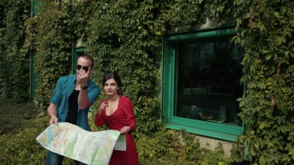 Молода пара закохана, дівчина і чоловік, тримає карту міста, вирішує, куди піти — стокове відео