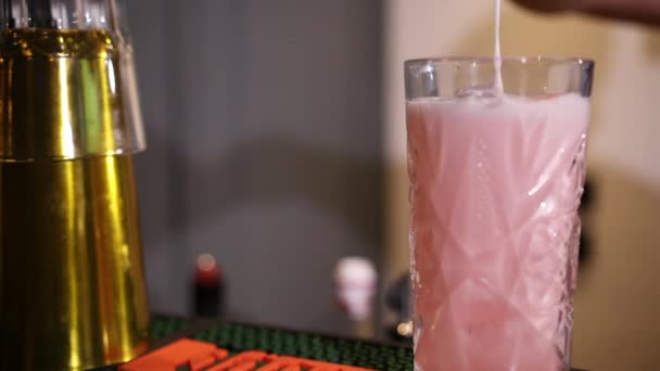 Camarero con una coctelera vierte un cóctel rosa en un vaso grabado con hielo — Vídeos de Stock