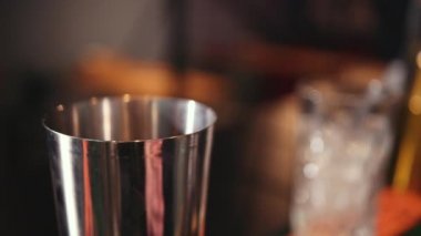 Bar tezgahı, barmen karıştırıcı kullanıyor ve çeşitli malzemeler kokteyl yapıyor.