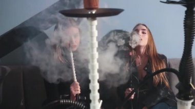 Kafede oturmuş nargile içen iki genç kız. Bir sürü kalın duman.