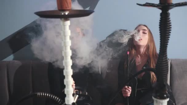 Дві молоді дівчата сидять у кафе, курять кальян. багато густого диму — стокове відео