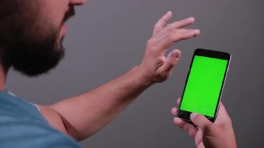 Elinde bozuk akıllı telefon tutan adam parmaklarını ekranda gezdiriyor.