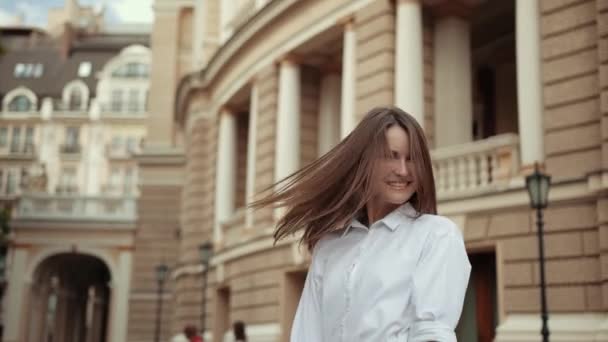 Młoda dziewczyna w białej bluzce, pozowanie z uśmiechem przed kamerą na ulicy — Wideo stockowe