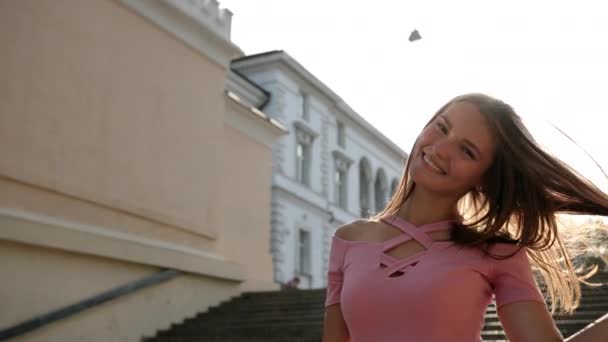 Ragazza in abito rosa, in posa con il sorriso davanti alla telecamera, in piedi sulle scale — Video Stock