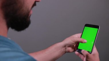 Elinde bozuk akıllı telefon tutan adam parmaklarını ekranda gezdiriyor.