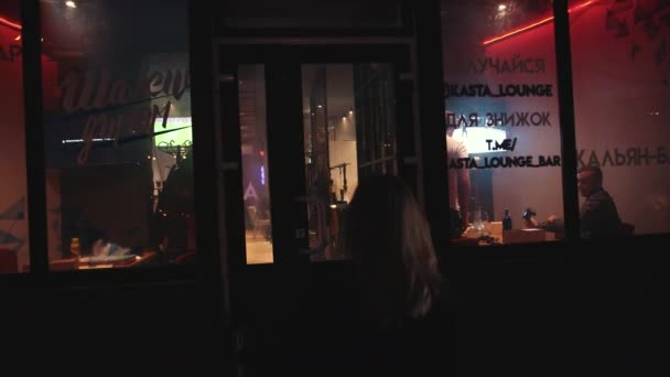 Young slender girl, walks into bar, opens door, where many men smoke hookah — Stock Video