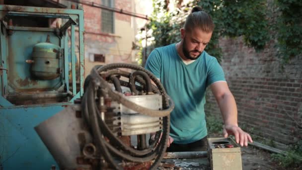 Man is worth near old buildings, clicks on button faulty, rusted mechanism — Stock Video