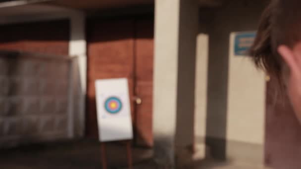 Guy shoots from string, wooden arrows with color end of fly target — Stock Video