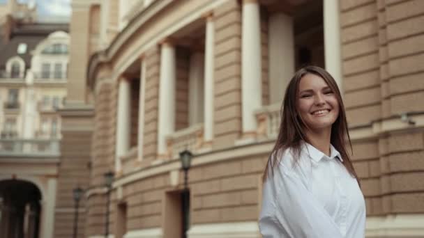 Ung flicka i vit blus, poserar med leende framför kameran på gatan — Stockvideo