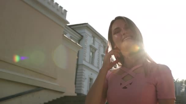 Chica en vestido rosa, posando con sonrisa delante de la cámara, de pie en las escaleras — Vídeos de Stock