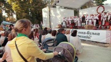 Sahnedeki insanlar, halk kostümlü kadınlar ve erkekler, şarkı söyleyin, akordeon çalın