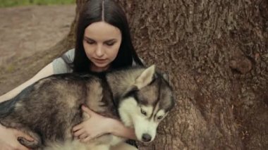 Çekici bir sarışın kadın parkta safkan Sibiryalı Husky Köpeğiyle oynuyor.