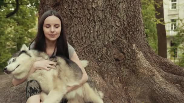 Uma jovem mulher loira atraente jogar com raça pura Siberian Husky Dog no parque — Vídeo de Stock