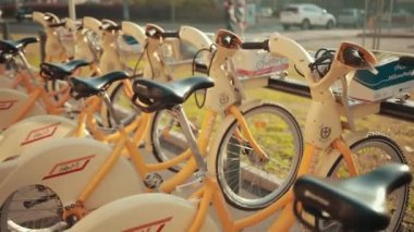 Otoparka çok sayıda sarı bisiklet park edilmiş vaziyettedir. Araç Başına Kiralama.