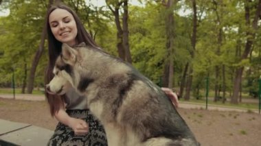 Çekici bir sarışın kadın parkta safkan Sibiryalı Husky Köpeğiyle oynuyor.