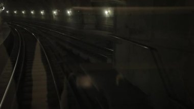Karanlık yeraltı tren tüneli, derinlerde, metro vagonu raylarda ilerliyor.