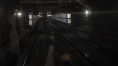 Karanlık yeraltı tren tüneli, derinlerde, metro vagonu raylarda ilerliyor.