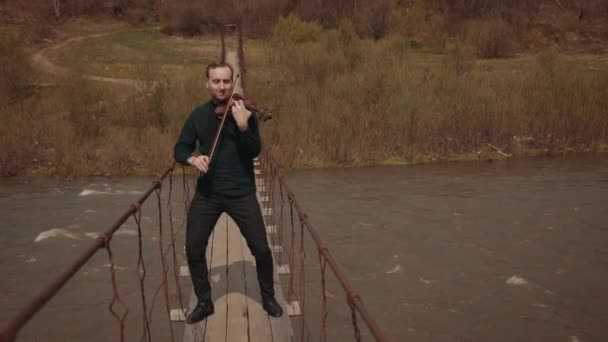 Violinist on the bridge, street Performer playing violin, outside. Swift river — Stock Video