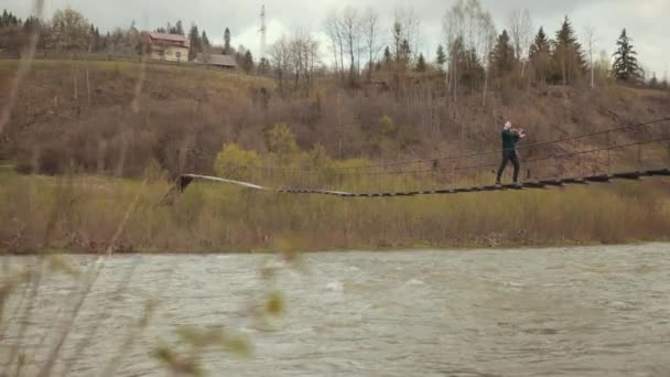 Houslista na mostě, pouliční herec na housle, venku. rychlá řeka — Stock video