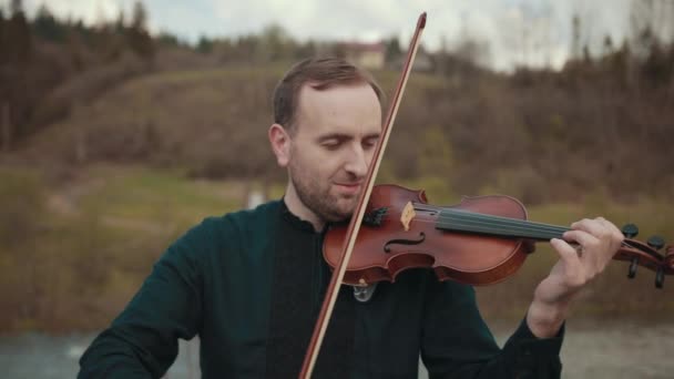 Violinista sul ponte, interprete di strada che suona il violino, fuori. Fiume Swift — Video Stock