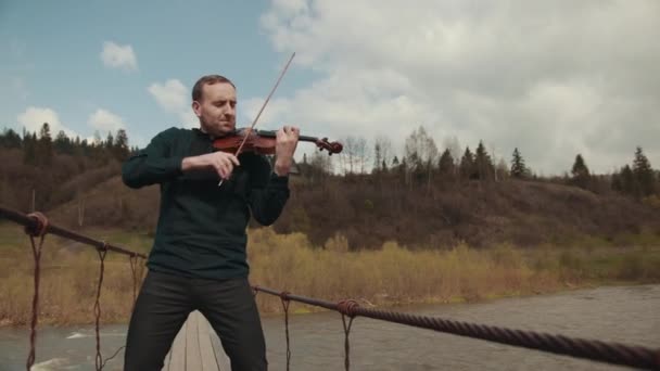 Violinist på bron, street Performer spelar fiol, utanför. snabb flod — Stockvideo