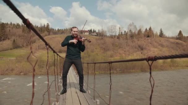 Violinista en el puente, intérprete de la calle tocando el violín, afuera. Río Swift — Vídeo de stock