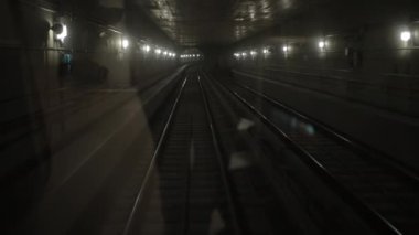 Karanlık yeraltı tren tüneli, derinlerde, metro vagonu raylarda ilerliyor.