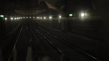 Karanlık yeraltı tren tüneli, derinlerde, metro vagonu raylarda ilerliyor.