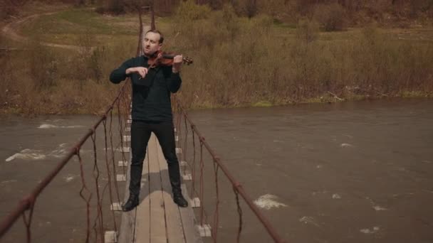 Violinist on the bridge, street Performer playing violin, outside. Swift river — Stock Video
