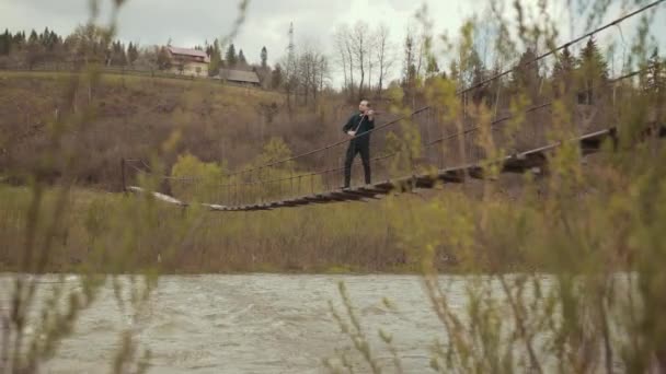 Pemain biola di jembatan, pemain jalanan bermain biola, di luar. sungai cepat — Stok Video