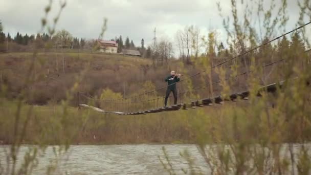 Violinist on the bridge, street Performer playing violin, outside. Swift river — Stock Video