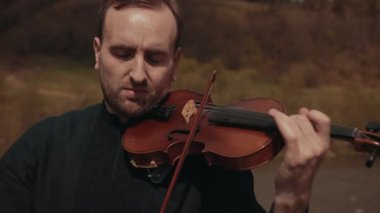 Köprüde kemancı, sokak sanatçısı, dışarıda keman çalıyor. hızlı nehir