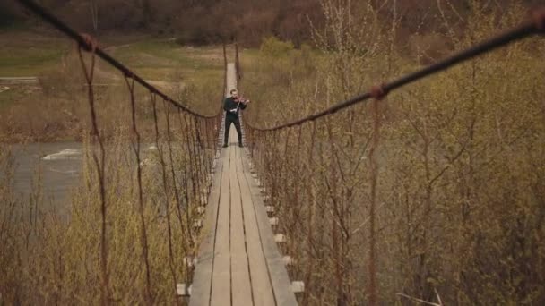 Violinista en el puente, intérprete de la calle tocando el violín, afuera. Río Swift — Vídeo de stock