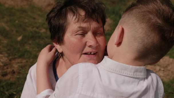 Petit-fils s'approche de la grand-mère. Il lui met son bras autour du cou. amour grand-mère — Video