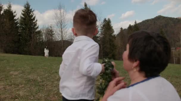 Ein kleiner Junge läuft von der Großmutter zu seiner Mutter, umarmt sie. Verwandte Generationen. — Stockvideo