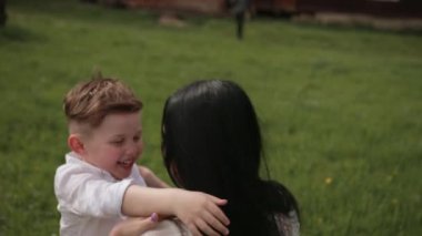 Eğleniyor, küçük çocuk annesiyle parkta oynuyor, annesi de küçük oğlunu oynuyor.