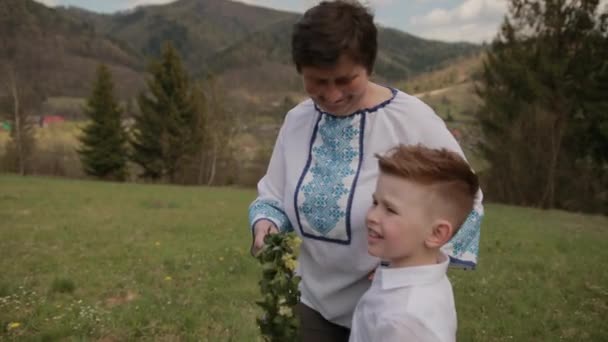 Enkel unterstützt Oma beim Gehen, Enkel geht durch die Natur — Stockvideo