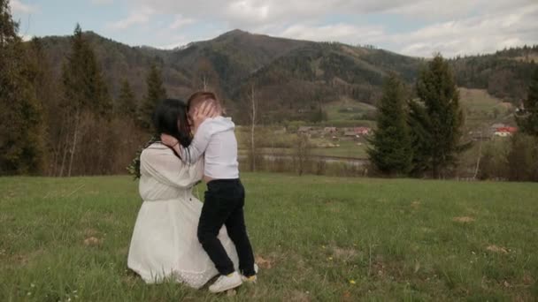 Nahaufnahme liebevolle junge Mutter umarmt, beruhigt kleinen Sohn, der im Freien weint — Stockvideo