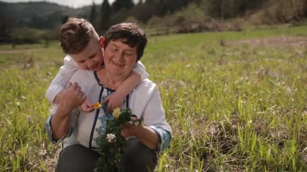 Kleinzoon benadert de grootmoeder. Hij doet zijn arm om haar nek. liefde oma — Stockvideo