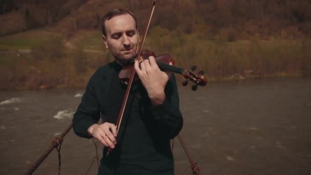 Violinista sul ponte, interprete di strada che suona il violino, fuori. Fiume Swift — Video Stock