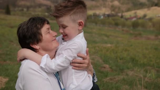 Az unoka közeledik a nagymamához. A nyaka köré fonja a karját. Szerelmes nagyi. — Stock videók
