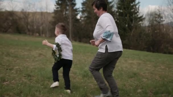 Enkel unterstützt Oma beim Laufen, Enkel geht durch die Natur — Stockvideo