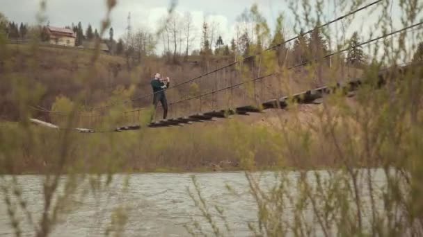 Viulisti sillalla, katuesiintyjä soittamassa viulua ulkona. nopea joki — kuvapankkivideo